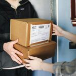 Close-up of hands exchanging cardboard boxes indoors, symbolizing delivery service.
